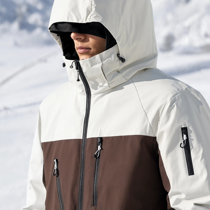 Gros plan sur le col et la capuche de la veste de ski blanche et marron