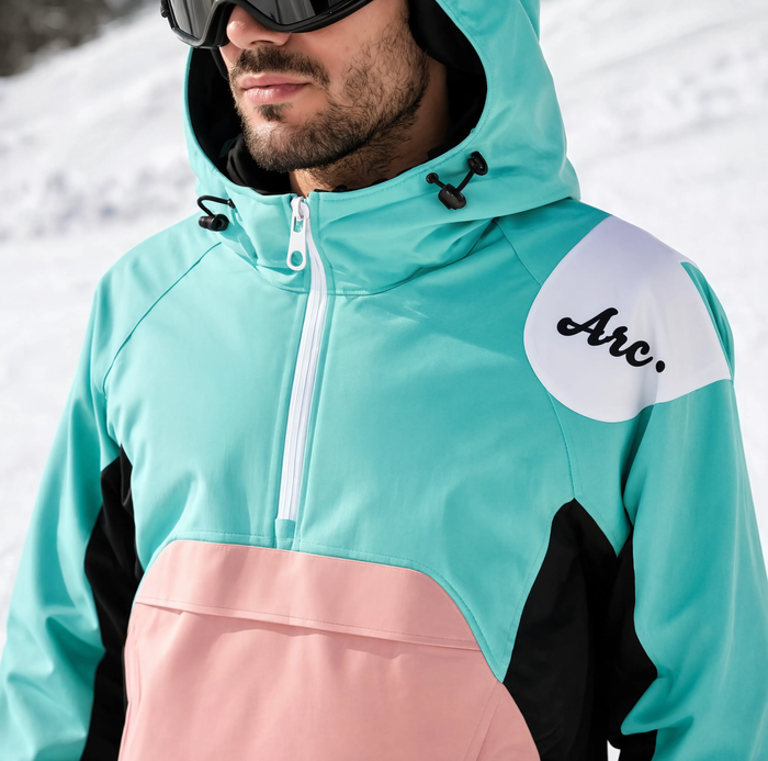 Gros plan sur le col et la capuche de la veste de ski turquoise et rose